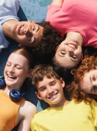 Group of happy teenagers kids outdoors on the sportive field at daytime